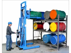 Man operating a blue MORStak Drum Racker, in front of a racking system that holds drums of various colors.