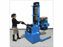 A person operating a large blue pilot power-propelled drum mover to transport a black drum vertically